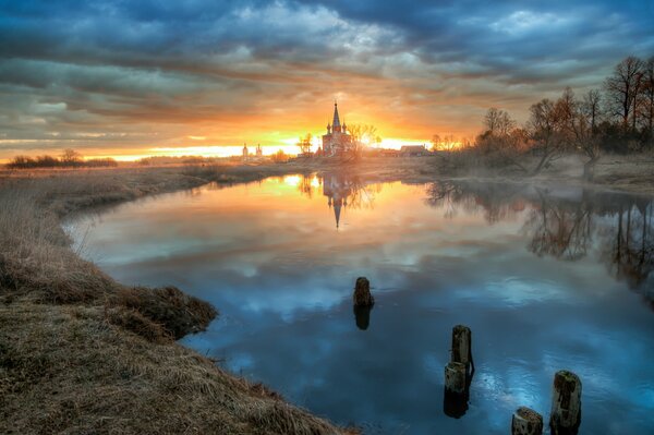 Church in front of a pond on the background of an orange dawn
