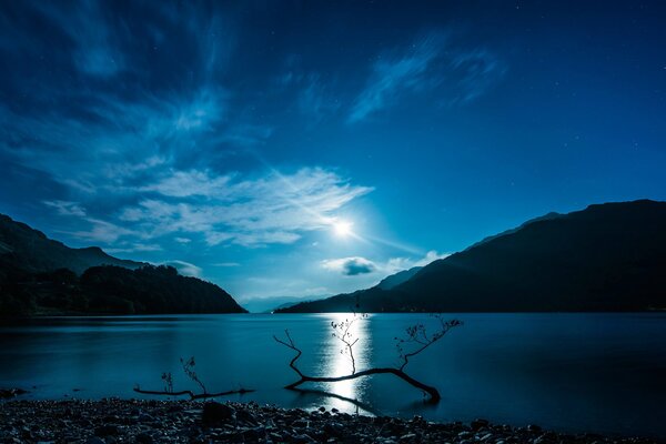 L acqua limpida lunare del lago in cui si riflettono le montagne della Scozia