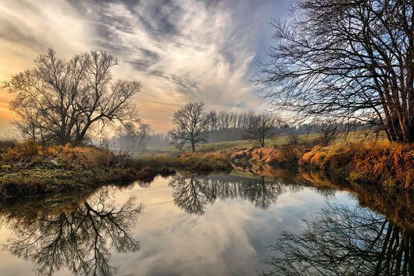 Herbsttapete mit Reflexion von Bäumen und Himmel im Fluss