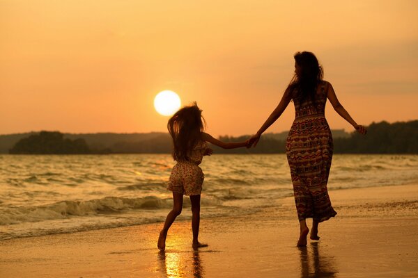 Mutter und Tochter gehen am Strand spazieren