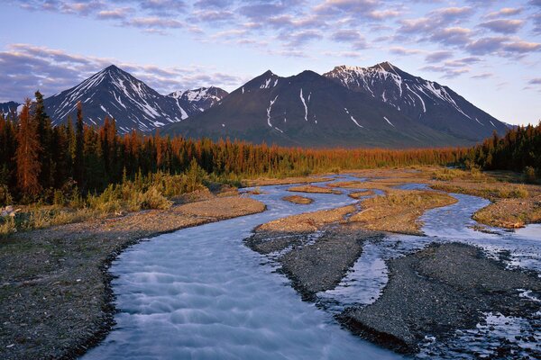 Le cours de la rivière près des montagnes au coucher du soleil