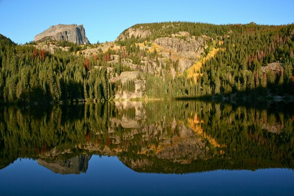 Reflejo de montañas y árboles en el lago