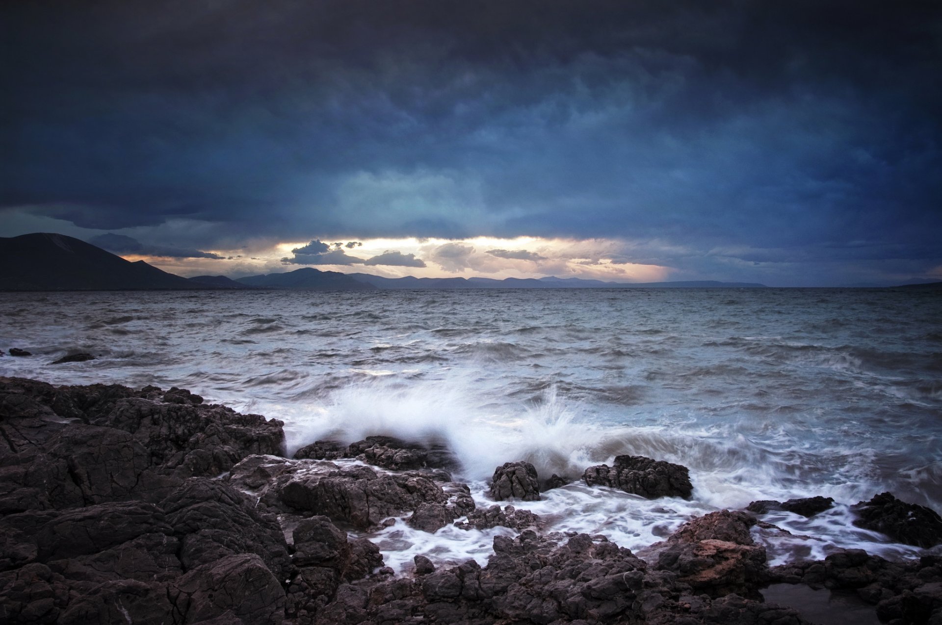 mar olas salpicaduras piedras montañas nubes