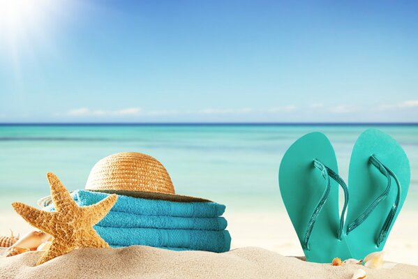 Beach accessories on yellow sand against a tropical sea background