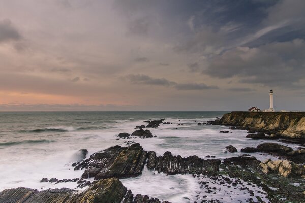 Foto di un faro. Bella foto di rocce e Oceano. Faro lontano sulla riva