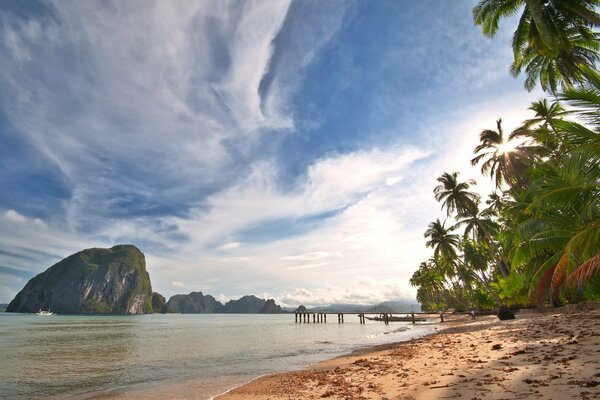 Пейзаж , пальмы на океане с видом на остров в море и берег с песком. Tropical beach вид на небо с облаками