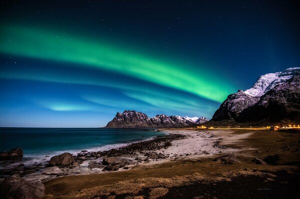 Northern lights on the seashore against the background of mountains