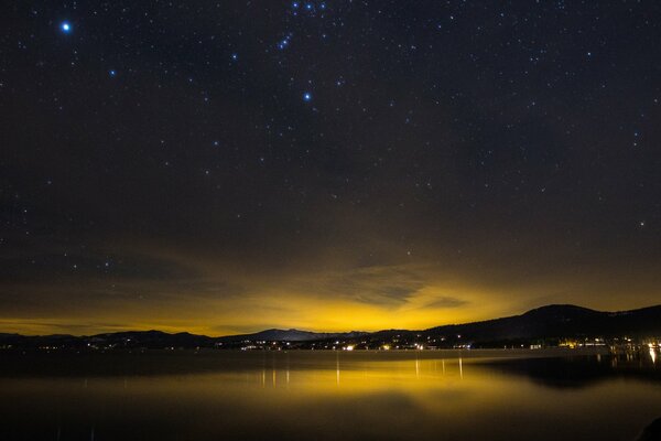 A night city under a starry sky covered with a yellow sunset