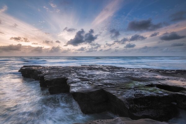 Las olas azules del oleaje golpean la costa rocosa