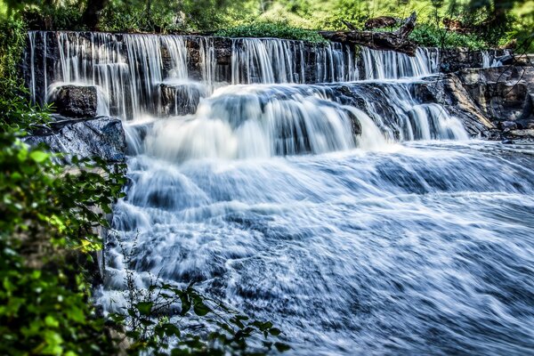 Hochwertiges Foto des Wasserfalls auf dem Hintergrund der grünen Landschaft