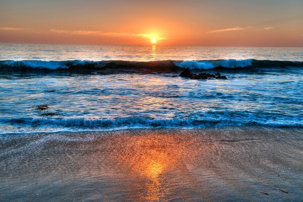 Le coucher du soleil et les vagues battent le rivage