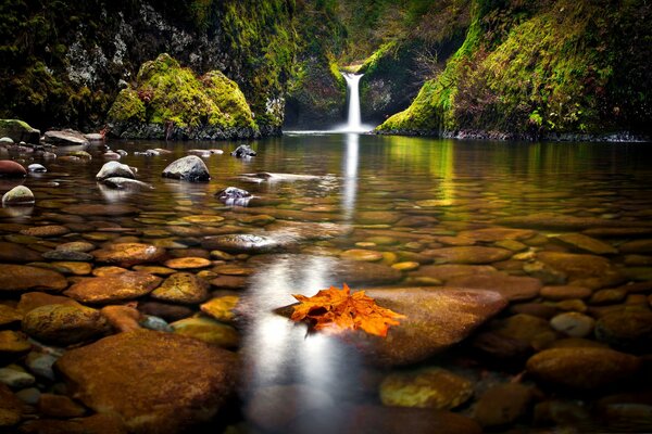 A rocky lake with a small waterfall in autumn