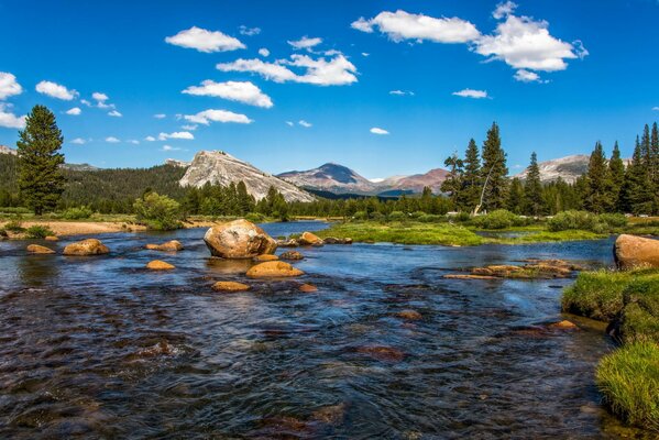 Berge vor dem Hintergrund des Sommerwolkenhimmels und des Flusses