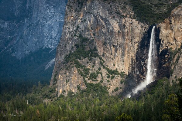 Schöne Draufsicht auf einen Wasserfall in den Bergen und das Meer
