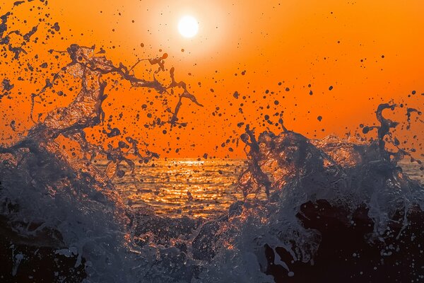 Sea spray of the sea on the background of a bright sunset