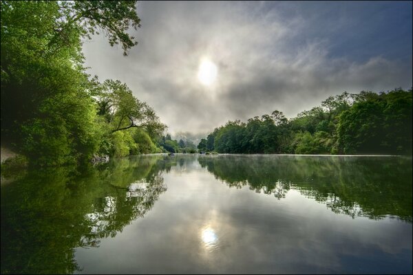 Die Sonne und die Bäume spiegeln sich im Fluss wider