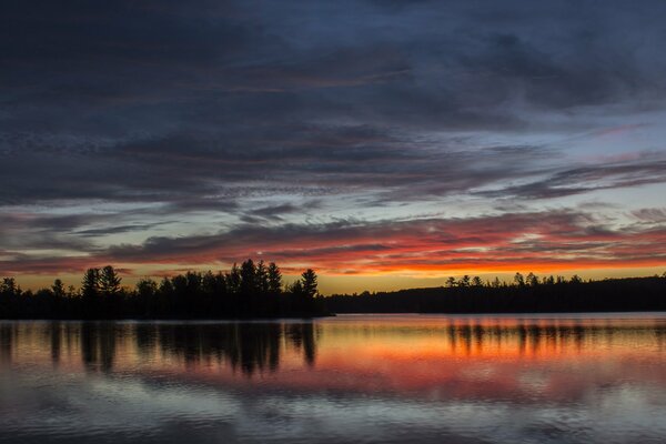 Naturaleza puesta de sol en el lago y el bosque en el horizonte