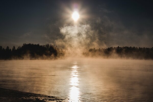 Amanecer en el lago en la niebla fría