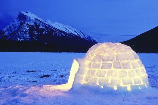 Yurta helada con luz en la nieve por la noche