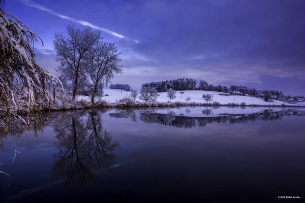 Widok na jezioro i śnieżny pagórek z drzewami