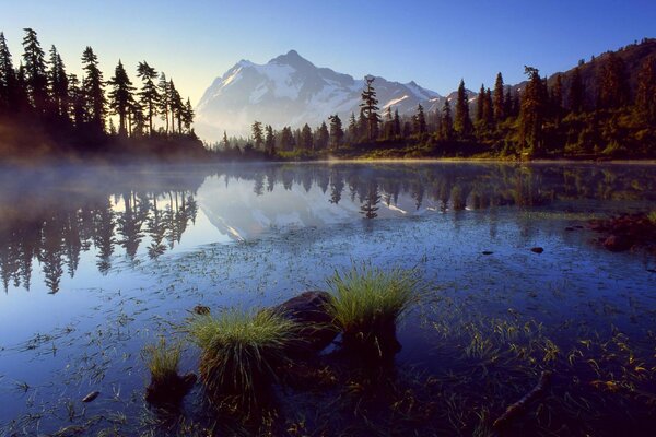 Sur le lac, les montagnes, le brouillard, les sapins sont visibles