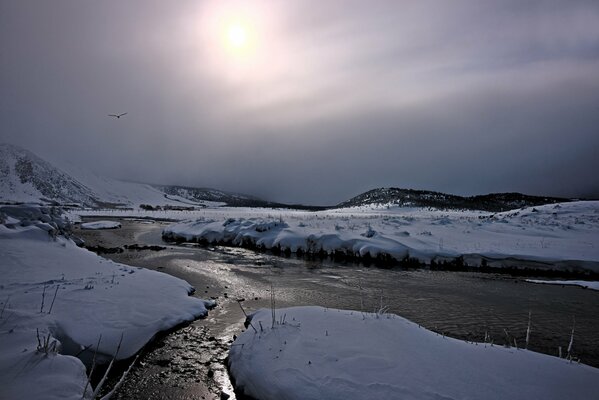 Fiume invernale con neve sulla riva