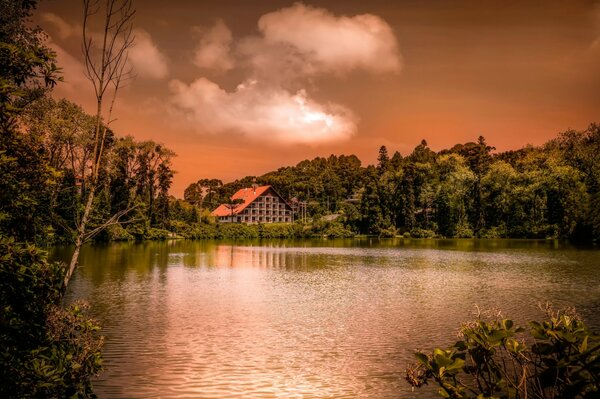 A house with a red roof on the lake shore