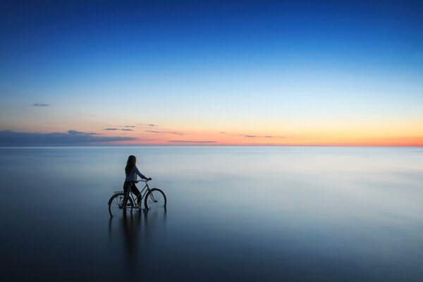 Una ragazza con una bicicletta entra in acqua