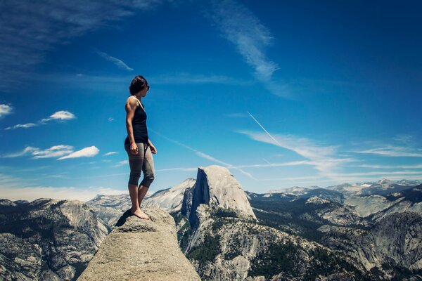 A girl standing over a cliff in a picturesque valley