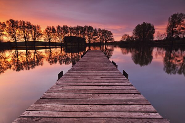 Il tramonto viola illumina il molo nel lago