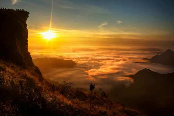 In Laos sieht man die Sonne zwischen Wolken und Felsen