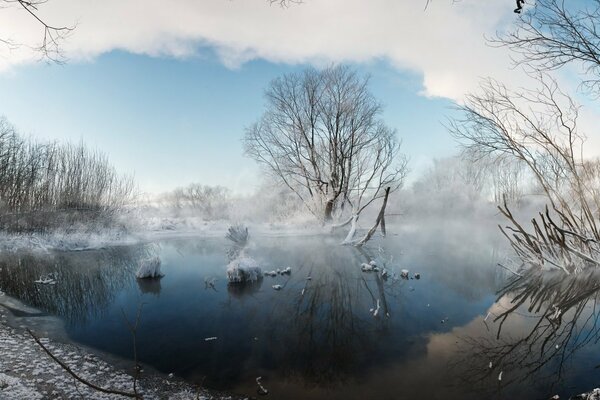 Paisaje de invierno. Niebla sobre el lago por la mañana helada