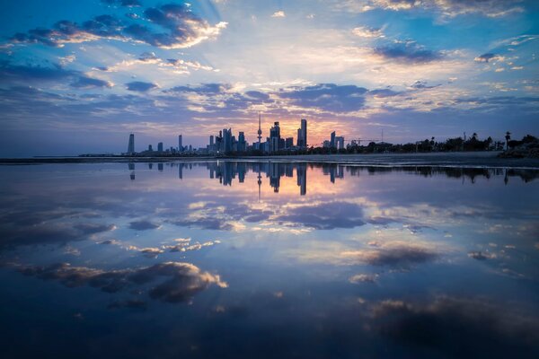 The city and clouds are reflected in the pond