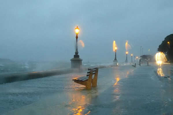 Banco solitario en el paseo marítimo en una tormenta a la luz de las linternas