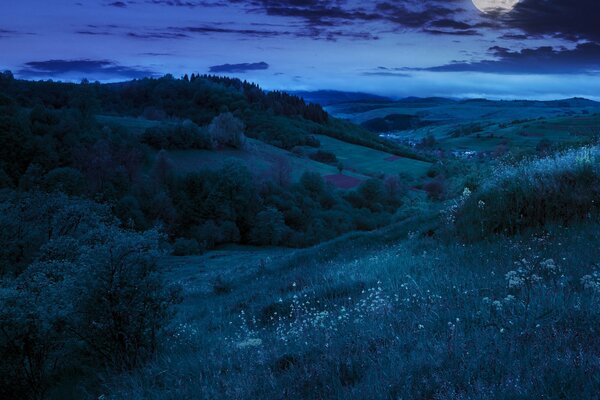 Pełnia księżyca nad nocną doliną ze wzgórzami
