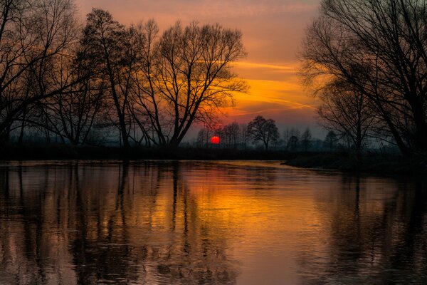 Ein feuriger Sonnenuntergang spiegelt sich im Fluss wider