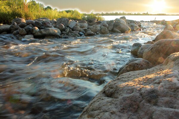 L écoulement rapide de l eau à travers les rochers vers le soleil. Photo rivière