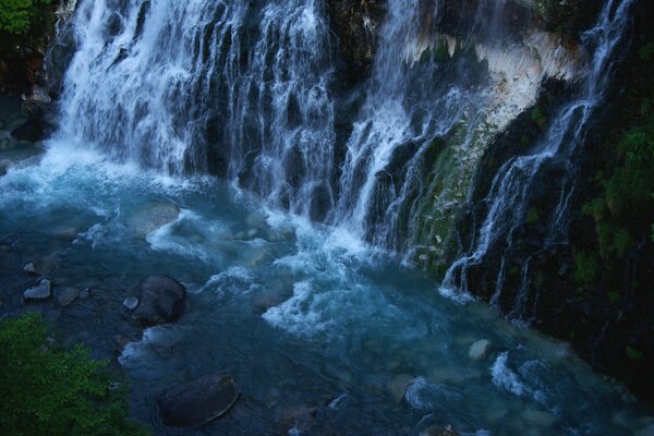 The rocky shore under the waterfall at dusk