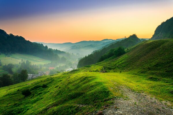 Un claro verde en las montañas en el fondo de la puesta de sol