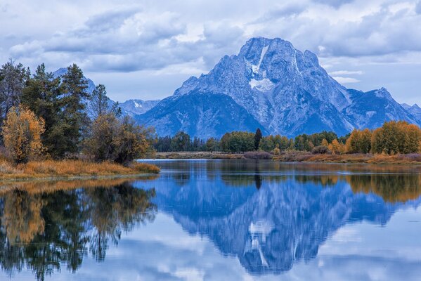 Bellissimo paesaggio di montagna con foresta autunnale che si riflette nella calma superficie del Lago