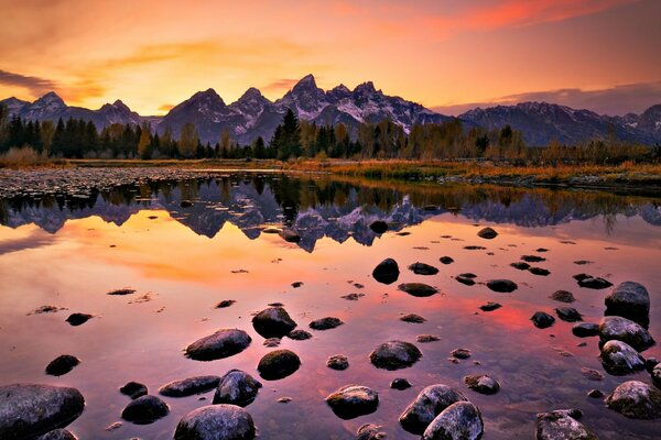 Stones in the water against the background of mountains in the setting sun