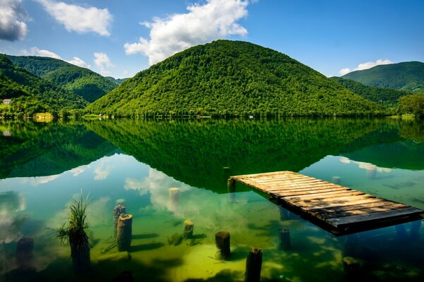 Reflejo de las verdes colinas en el lago