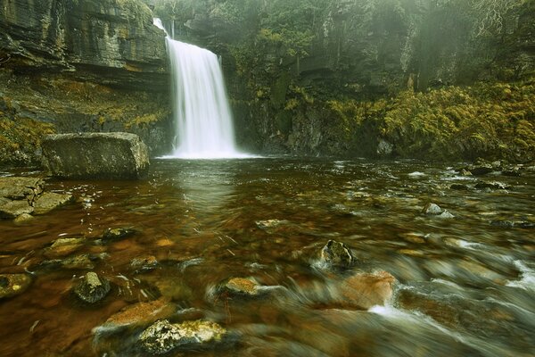 Waterfall flow into the river from a cliff