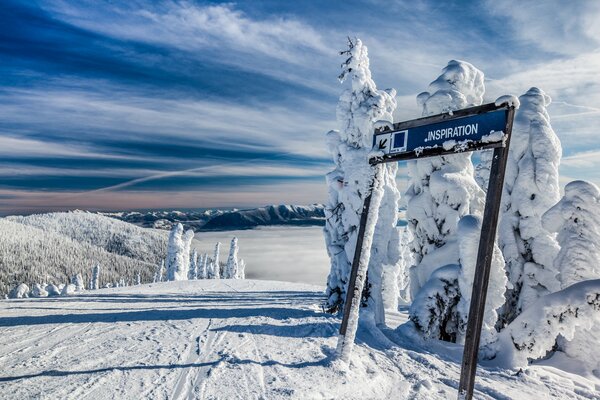 A signpost on a snow-covered road in the mountains