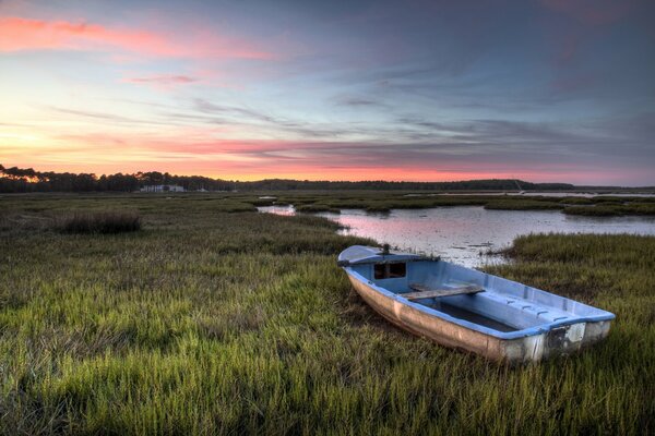 Boot am See und rosa Sonnenuntergang