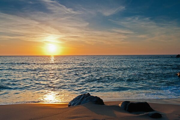 Steine in den Armen von Strandsand bei Sonnenuntergang