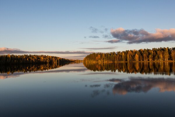 Auf einem breiten Fluss werden Wolken im Wald angezeigt