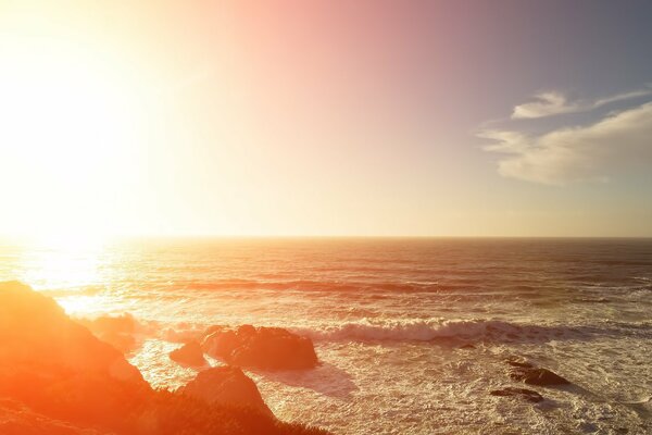 Raging waves reflected from the sun beat against the rocks