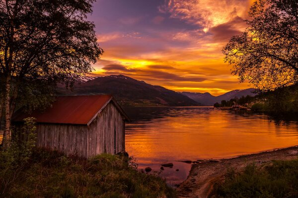 Cabane sur le lac au coucher du soleil en Norvège
