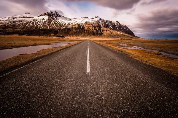 A deserted road leading to the snowy mountains